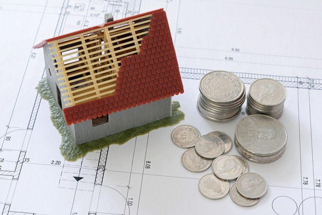 modellino casa in costruzione appoggiata sopra un progetto