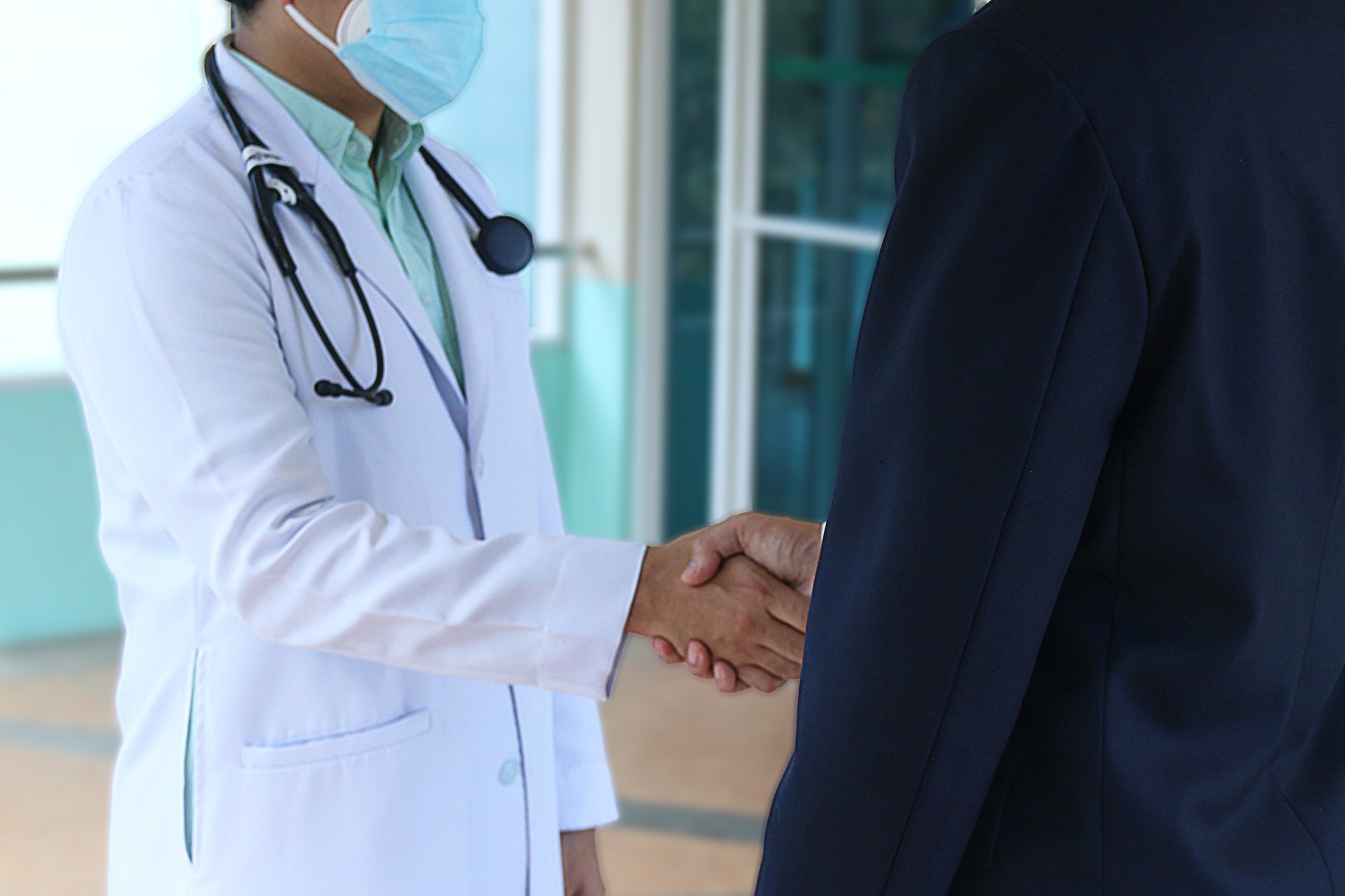 medico con camice bianco che stringe la mano all'assicuratore dopo aver firmato la polizza