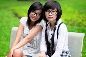 due ragazze cinesi sorridenti sedute su una panchina