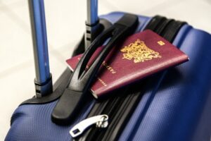primo piano del manico di una valigia rigida di colore blu, Nel manico è appoggiato un passaporto rosso