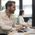 Professionista alla scrivania consulta un documento sulla registrazione EMAS in un ufficio moderno e sostenibile