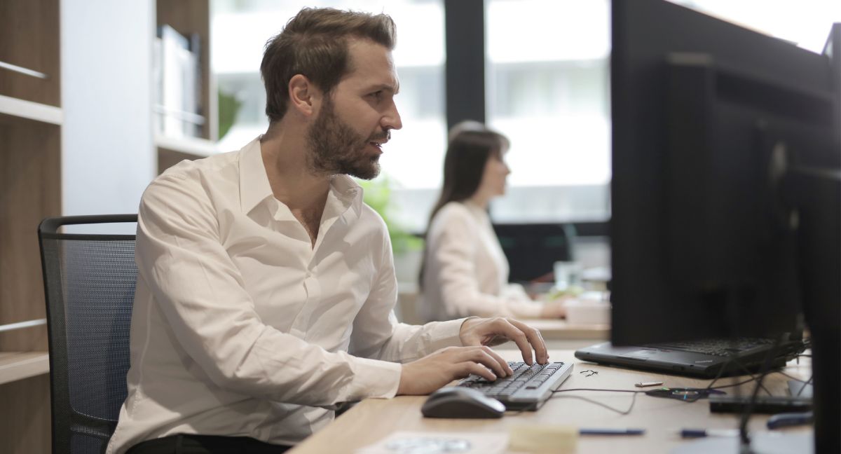 Professionista alla scrivania consulta un documento sulla registrazione EMAS in un ufficio moderno e sostenibile