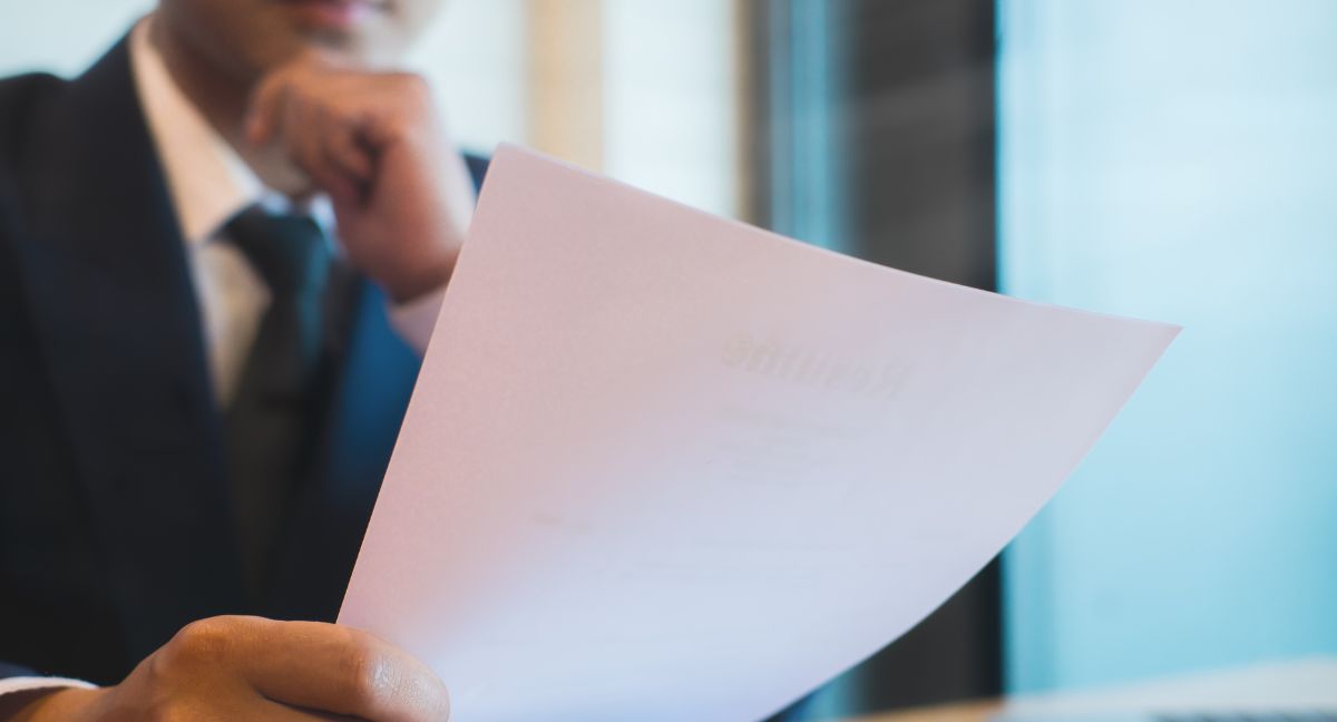 Imprenditore e consulente esaminano documenti digitali sul Codice Appalti 2023-2025 con tablet, laptop e fideiussioni in ufficio